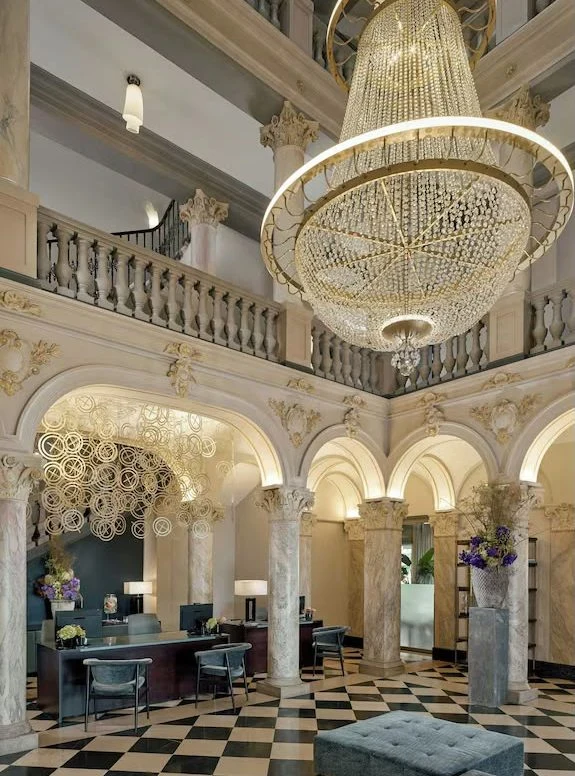 A marble hotel lobby with a crystal chandelier