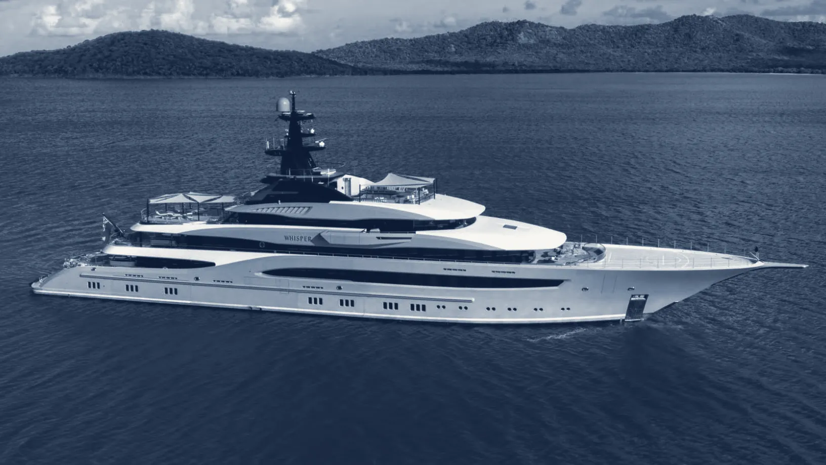 A superyacht beside a green coastline